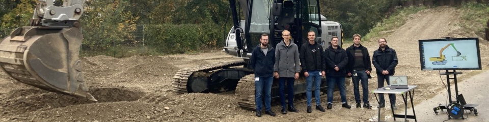 Die fünf Studenten des Masterstudiengangs Software Engineering der Universität Ulm mit dem Bagger, den sie programmiert haben.