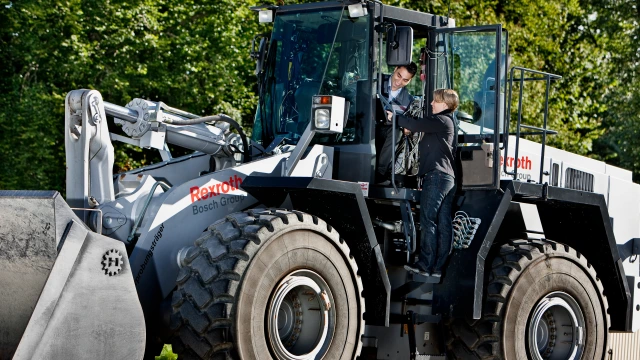 Ein Traktor in dem ein Mann sitzt und eine Frau die neben der offenen Tür des Traktors steht