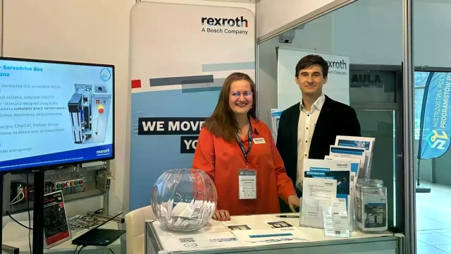 A woman and a man at the Bosch Rexroth booth with a multimedia presentation, roll-ups, and brochures.