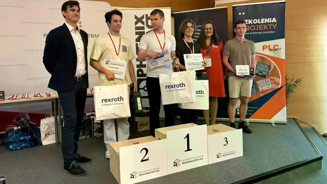 Competition participants and partners on stage with the podium and awards.
