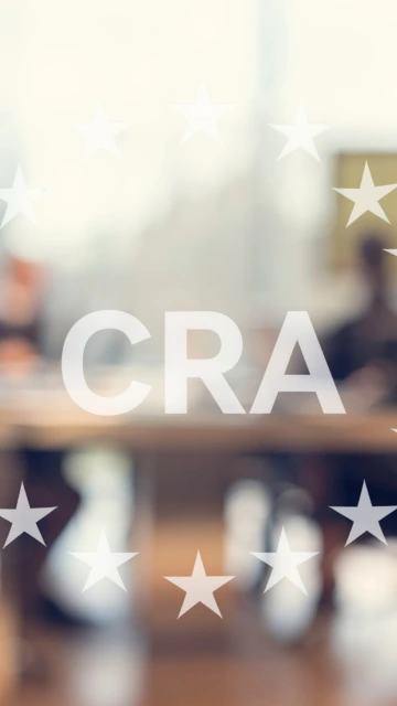 Oskarp bild av personer i ett konferensrum med CRA:s Europa-symbol överst i bilden. 