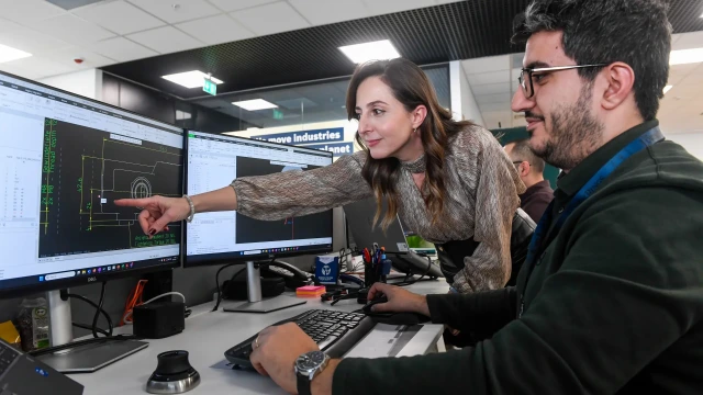 Bosch Rexroth Bursa Tasarım Merkezi'nde bir mühendis, meslektaşına teknik çizimler üzerinde yönlendirme yapıyor.