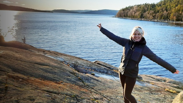 A person in the Bosch Rexroth graduate specialist program with arms outstretched in front of lake