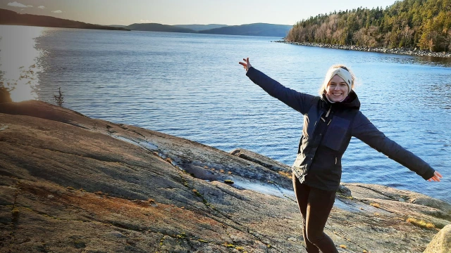A person in the Bosch Rexroth graduate specialist program with arms outstretched in front of lake