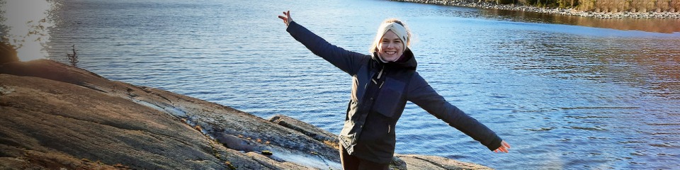 A person in the Bosch Rexroth graduate specialist program with arms outstretched in front of lake