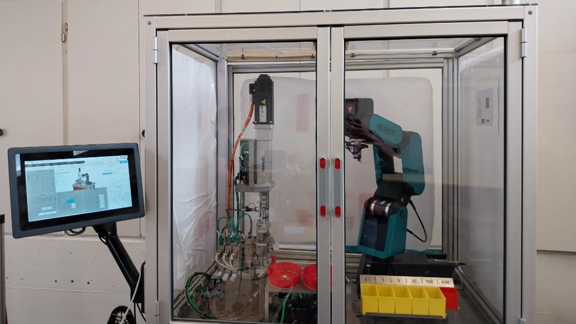 Robot in an enclosure alongside a screen with graphics