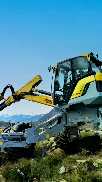 yellow-grey Menzi Muck M4x walking excavator in the mountains