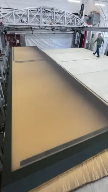 A voxeljet VX9000 3D printer filled with sand, with a person walking on it