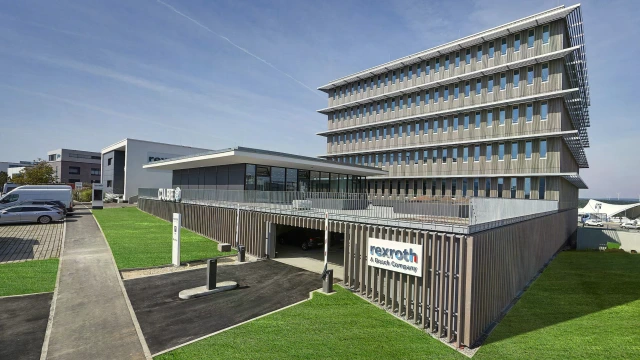 A large squared office building in sunny weather. There is grass surrounding the building and a large sign saying "Rexroth A Bosch Company"