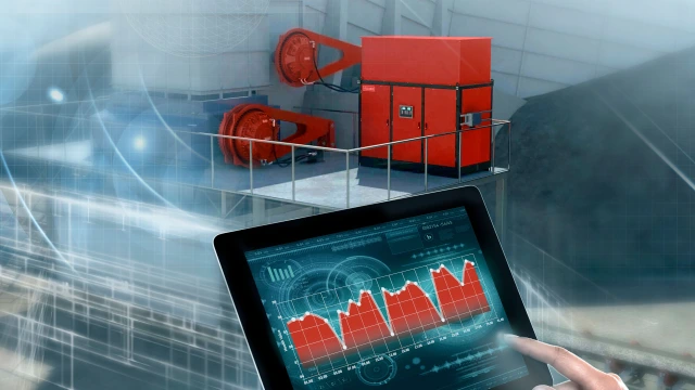 A Hägglunds direct drive system in the background and a tablet showing a graph of drive system data from condition monitoring.