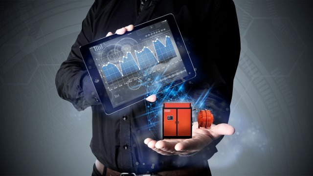 The torso of a man holding an iPad with graphs in one hand and a vision of a Hägglunds drivve system in the other hand