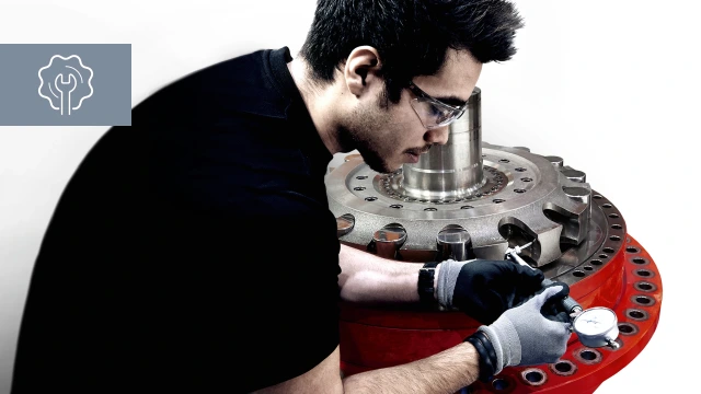 Dark haired male technician conducting service on hydraulic motor