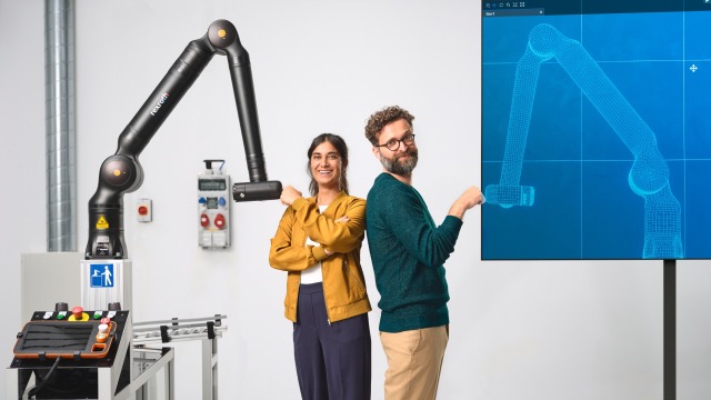Two people in front of a robot looking at each other