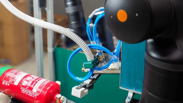 Cobot labeling a fire extinguisher.