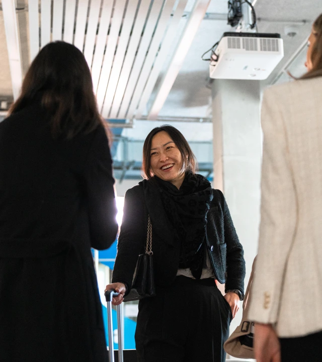 Three women engaged in conversation at an airport.