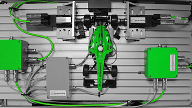 Ein kleines, grünes Rennauto-Modell, montiert auf einem Teststand mit Sensoren, Kabeln und zwei grünen OPVengineering Modulen.