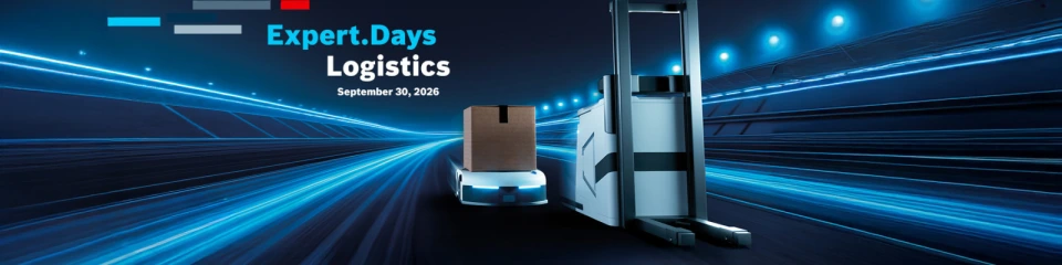 The image shows an autonomous transport robot carrying a cardboard box and an automated forklift