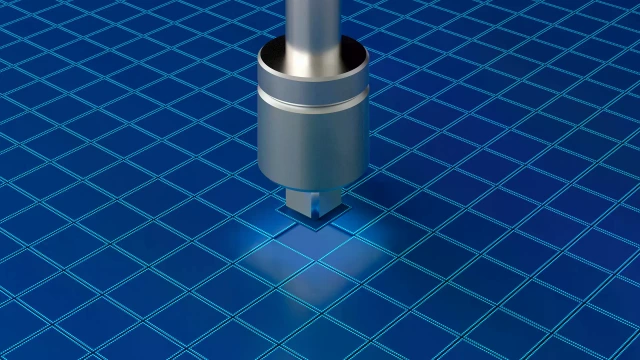 Eine einzelne Metallsonde, die direkt über einem blau gemusterten Siliziumwafer positioniert ist.