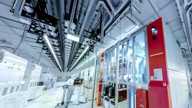 Weitwinkelansicht eines großen, hell erleuchteten Reinraums mit weißen Böden und Decken sowie komplexen Industrieanlagen.