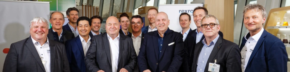 At the signing in Lyon: Dr. Steffen Haack, CEO of Bosch Rexroth (at the table, right), Rainer Keiemburg, Vice President Greases & Specialties, TotalEnergies Lubricants (at the table, left).