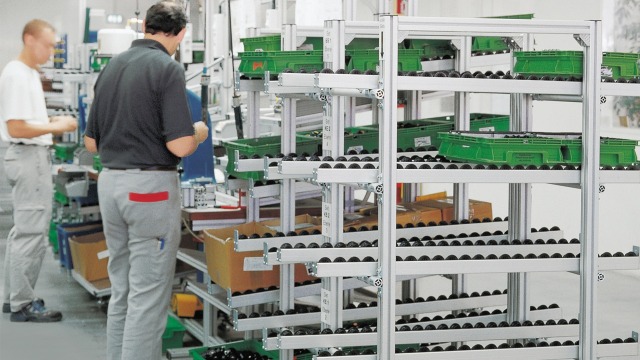 Työntekijä työskentelemässä keräilyasemilla, joilla on Bosch Rexrothin kanban- läpivirtaushyllyt