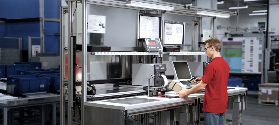 Man standing infront of a workstation scanning a package