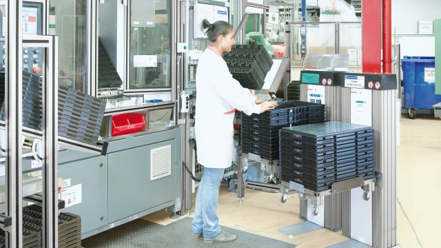 Mitarbeiterin arbeitet an einem Arbeitsplatz von Bosch Rexroth mit elektronischen Kistenhubgeräten