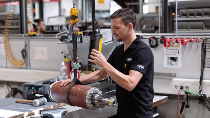 The picture shows a service employee in a workshop performing repair work on a motor.