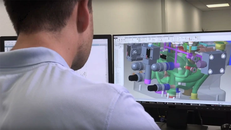 Employee in front of monitors during the digital planning of a manifold.