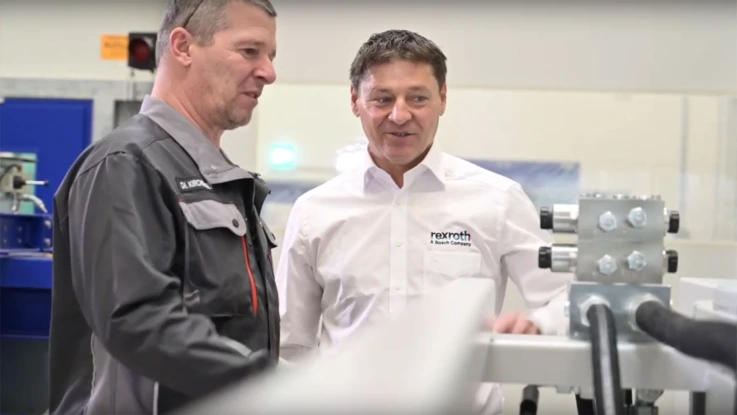 Two employees from Wittmann Battenfeld and Bosch Rexroth looking at a manifold.