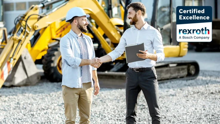 Socio y cliente final dándose la mano frente a una excavadora