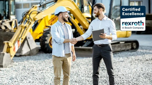 Partner and end customer shaking hands in front of an excavator