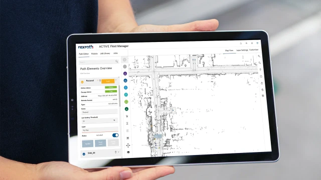 The picture shows a tablet in a person's hand. On the screen of the tablet, you can see the user interface of the ACTIVE Fleet Manager software.