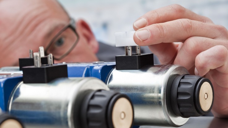 Mann arbeitet an einer Hydraulik-Komponente