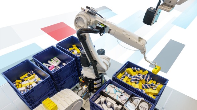 Industriroboter plukker opp en rekke ulike gjenstander fra fem kildebeholdere ved å bruke en sugegriper, og plasserer dem på et transportbånd.