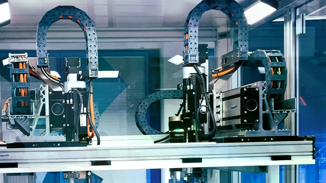 Foto eines Mehrachssystems sowie eines Transfersystems und Kettenfördersystems, auf dem die Batteriepacks und -module transportiert werden.