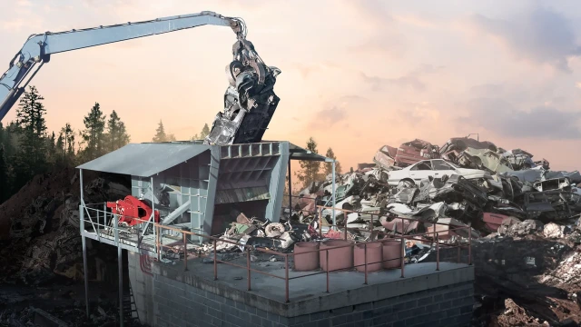 Un broyeur, propulsé par un entraînement direct rouge d’Hägglunds, déchiquetant une voiture dans une casse.