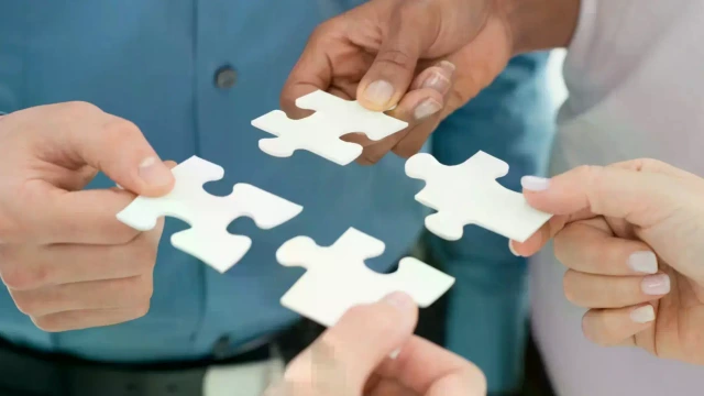 Mehrere Hände, die Puzzleteile passgenau zusammenführen.