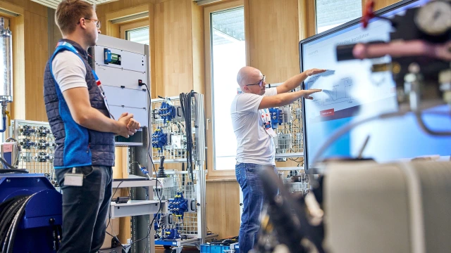 Trainer im Austausch mit einem Trainingsteilnehmer über die Technologie Mobilhydraulik.