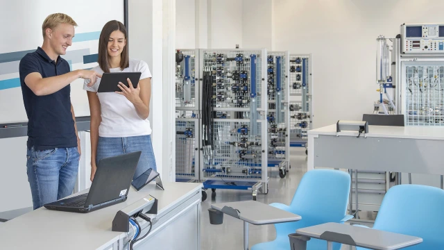 Ein Hydraulik-Trainer im Trainingsraum der Bosch Rexroth Academy berät eine interessierte Trainingsteilnehmerin über das weiterführende Trainingsangebot.